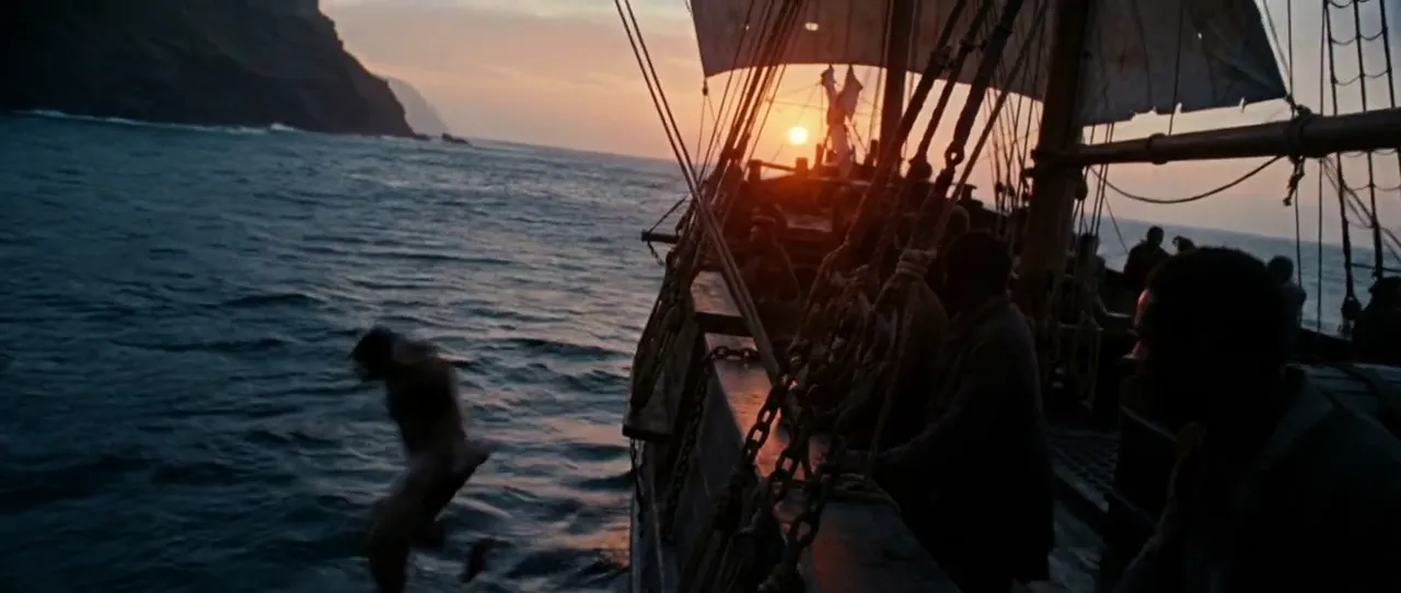 A figure leaping from a sailing ship into the sea at sunset