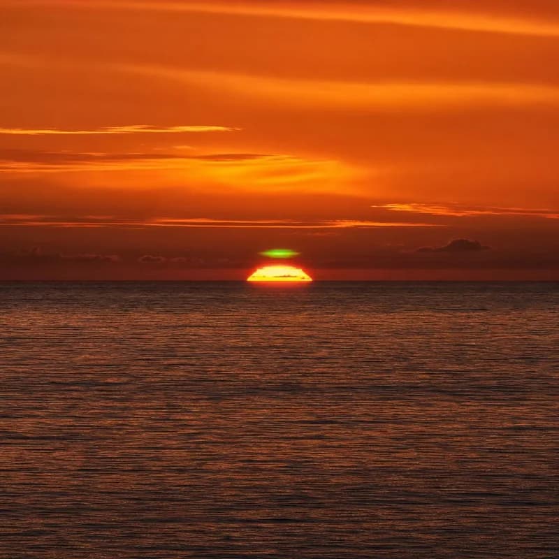 Green flash — the sky's rarest farewell. As the sun sinks below the horizon, atmospheric refraction bends its last light into a fleeting emerald spark. Blink and it's gone forever.